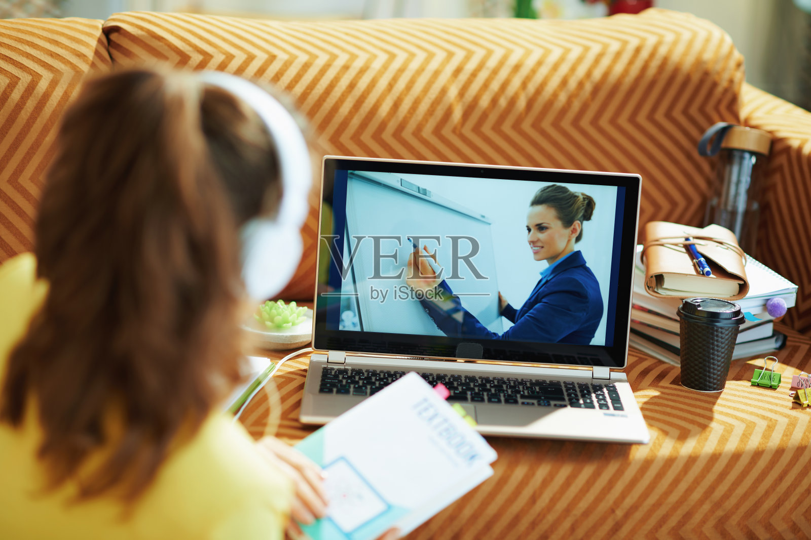 带着白色耳机和教科书的女子在网上上学照片摄影图片