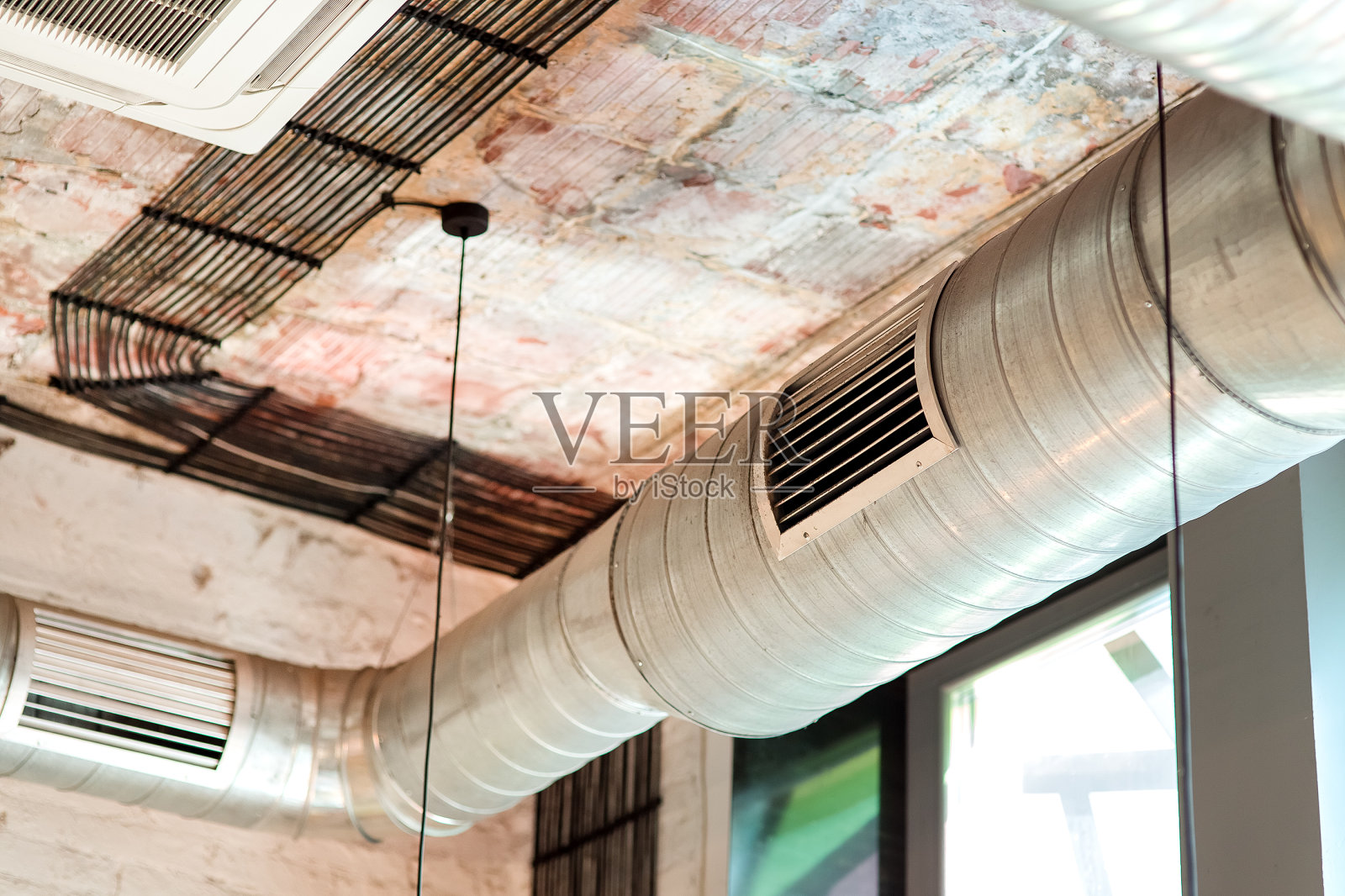 该房间的通风系统安装在建筑的天花板上,采用阁楼式的封闭管道和格栅。照片摄影图片