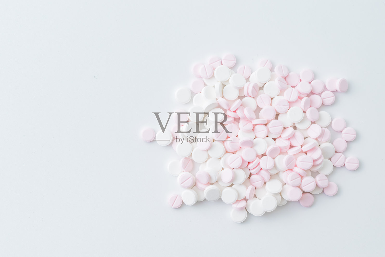 粉色和白色的药丸在浅色的背景上。医疗制药概念照片摄影图片