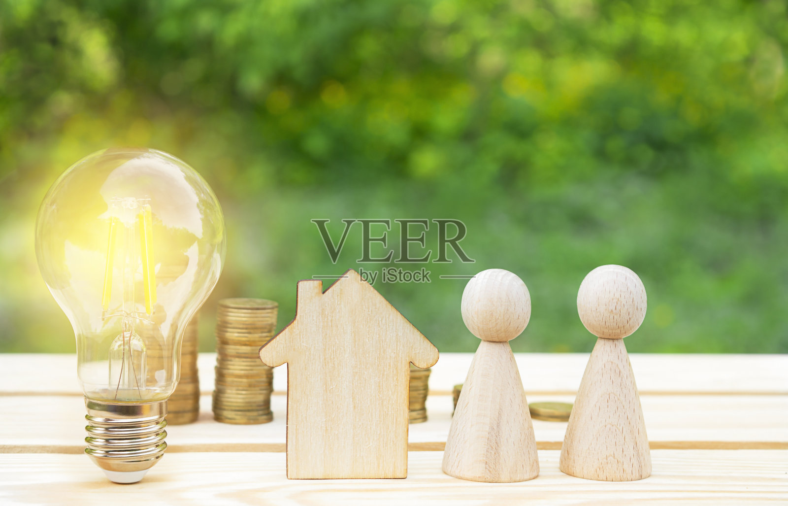 经营理念。家庭保险的概念。木制的房子,灯和木制的小男人在绿色的散焦背景木桌子上。公用事业支付,能源概念。副本的空间。照片摄影图片