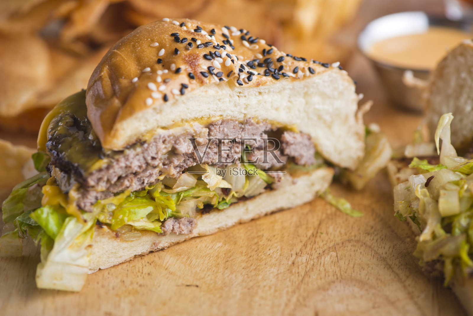 培根芝士汉堡。经典美式汉堡配牛肉饼、香脆培根、融化的瑞士和切达奶酪、焦糖洋葱、生菜、西红柿,配上烤好的奶油面包和酥脆的薯条。美国酒吧食物的最爱。照片摄影图片