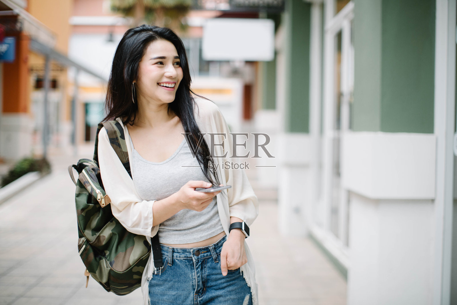 亚洲妇女使用智能手机在街道在一个阳光明媚的夏天照片摄影图片