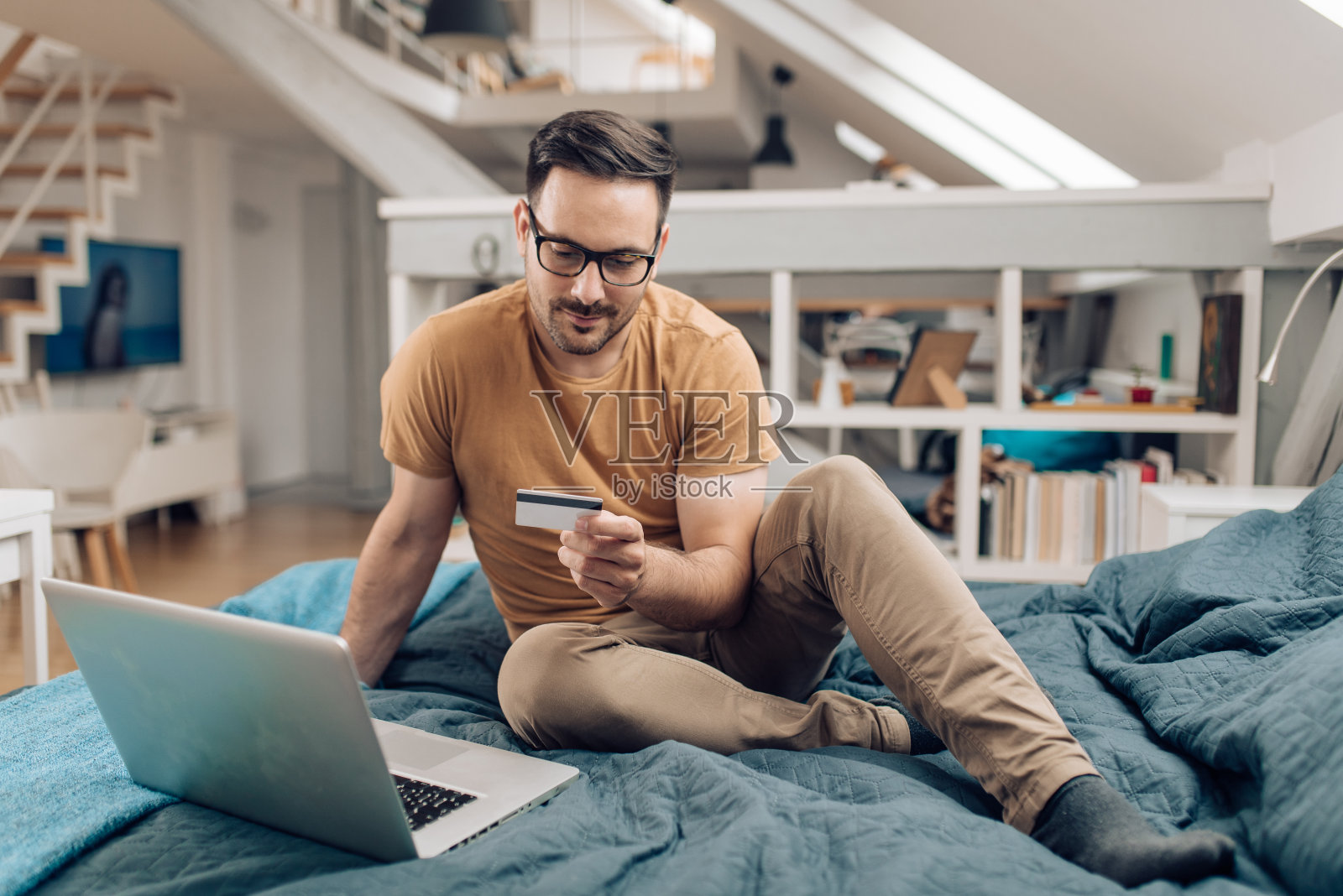 年轻人在床上放松,在网上购物照片摄影图片