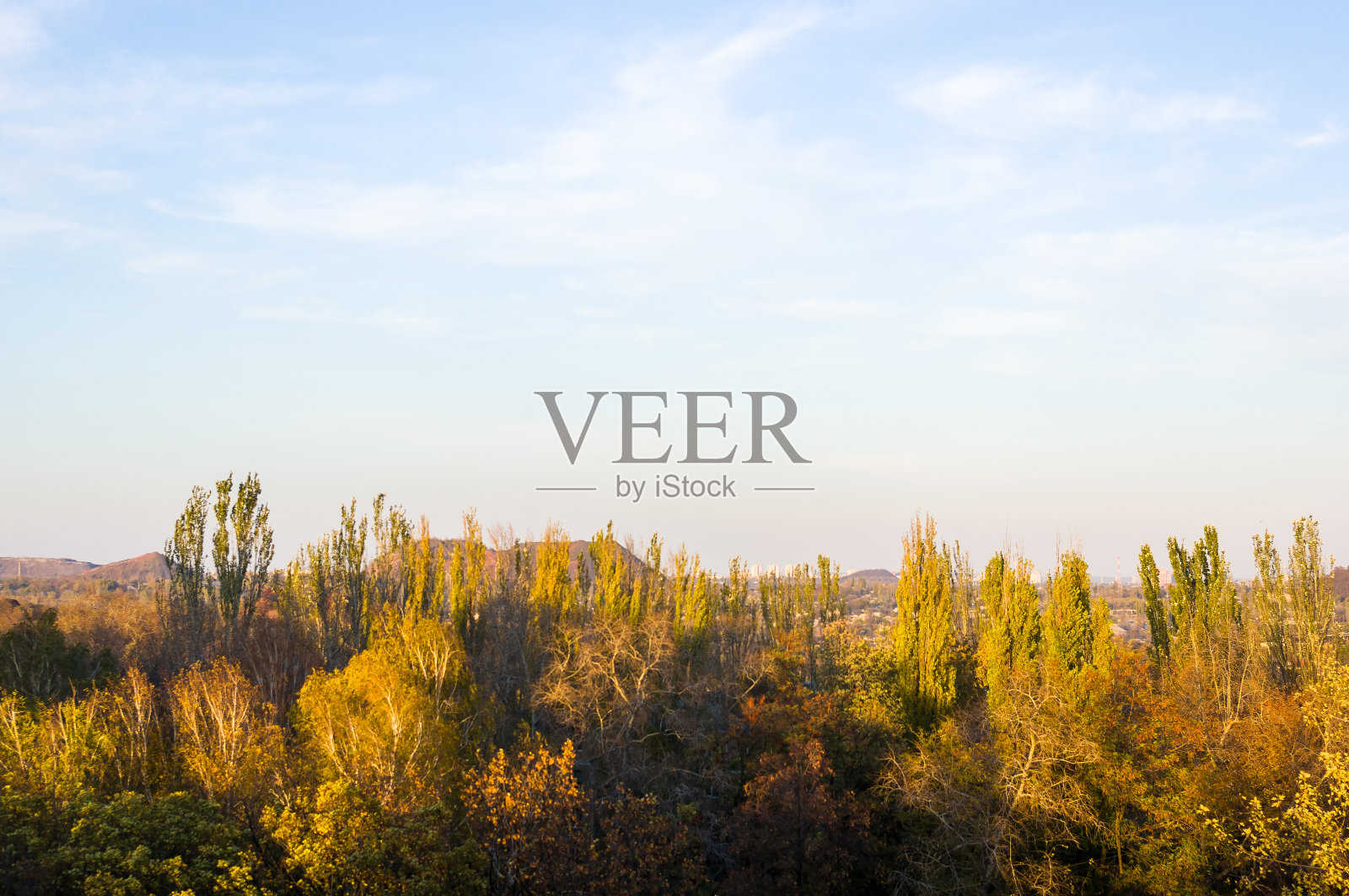 秋天的城市景观在一个阳光灿烂的日子——黄色和五颜六色的秋天的树木,天空与云与秋雾照片摄影图片