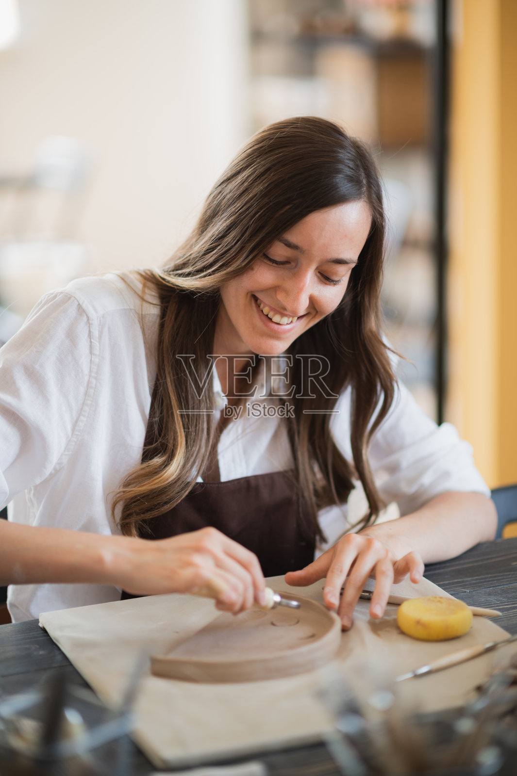 特写大师陶工,粘土切割专用工具。女艺术家用木环工具切割照片摄影图片