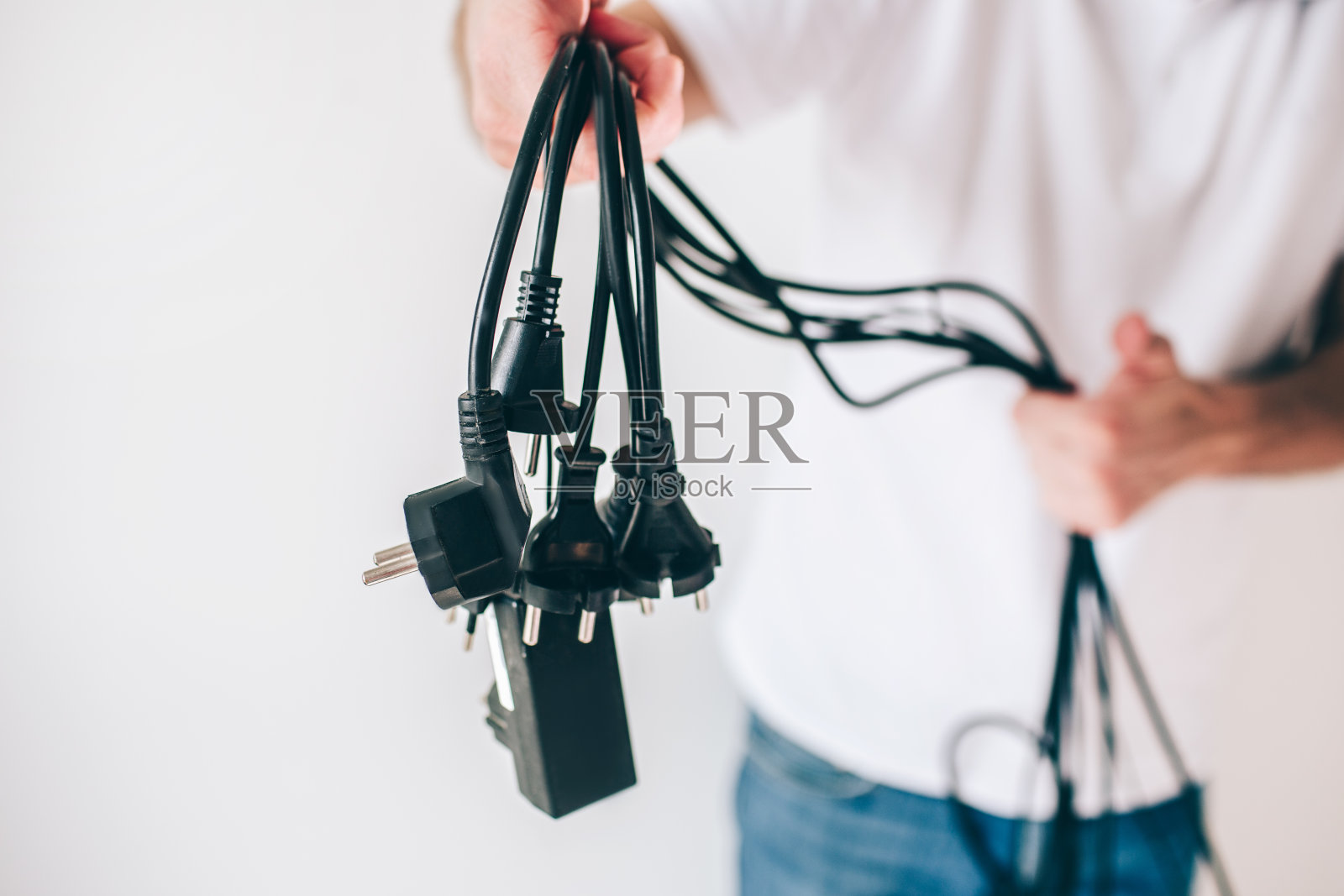 年轻人被孤立在白色背景下。剪视图和特写的家伙拿着黑色的电缆和电线在手里。照片摄影图片