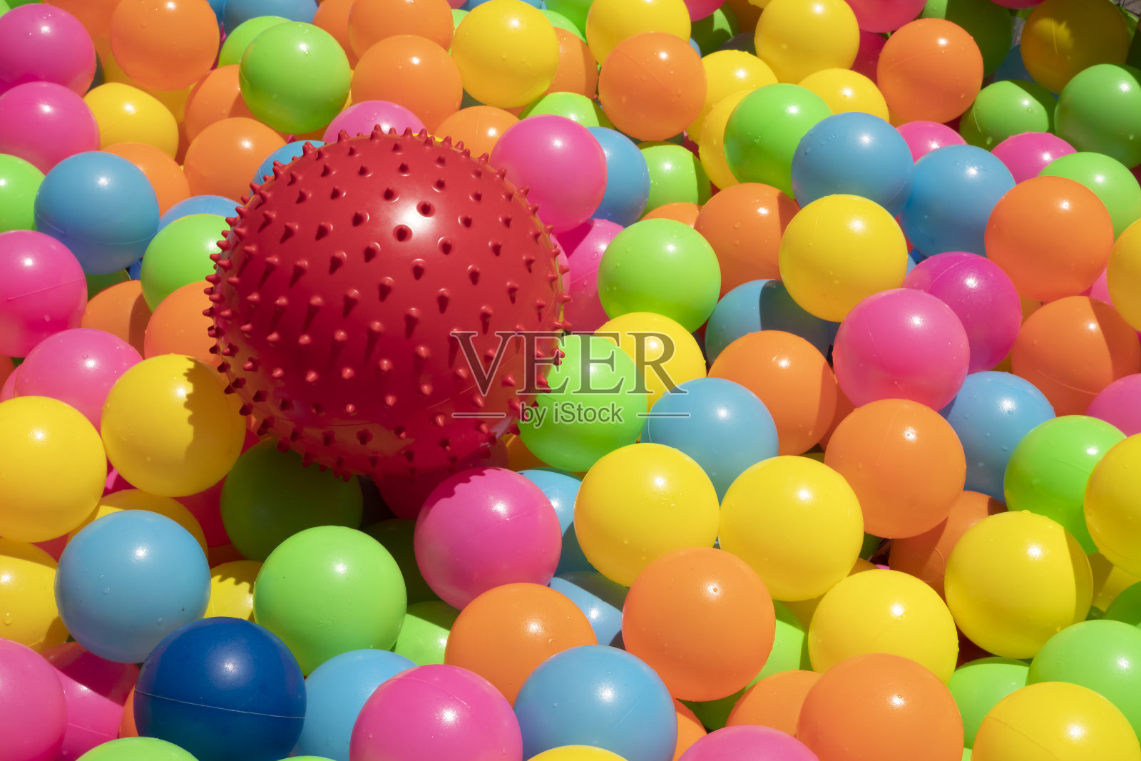 清洗红色带尖钉的橡胶玩具球和彩色塑料球,洗净水,暴露在阳光下照片摄影图片