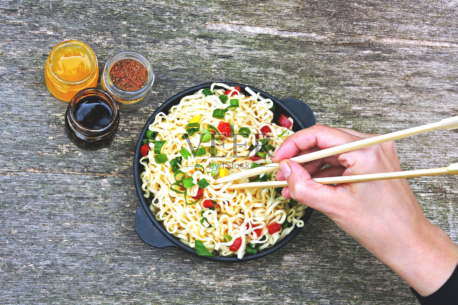 木架上的铸铁煎锅里的中式面条。照片摄影图片