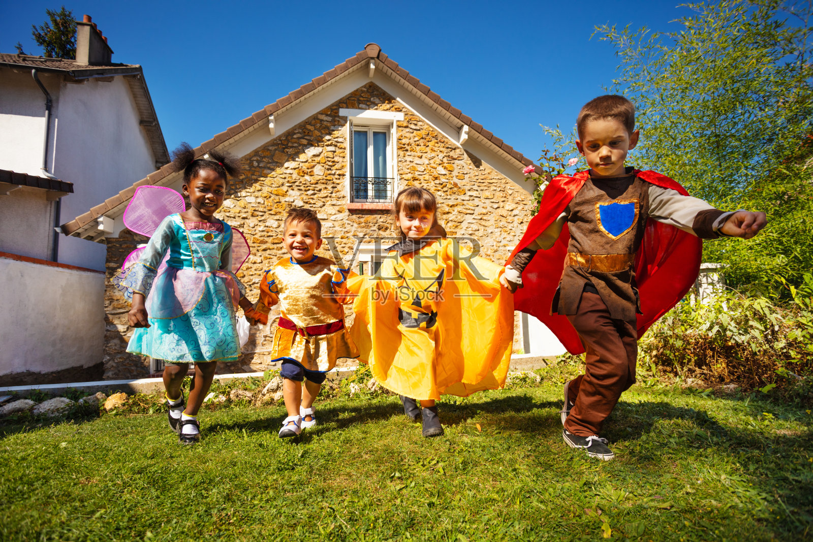 一群孩子穿着万圣节服装在草坪上奔跑照片摄影图片