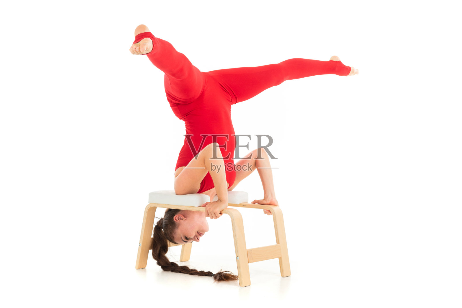欧洲黑发女孩在红色运动服希望体操练习倒挂在白色的背景。照片摄影图片