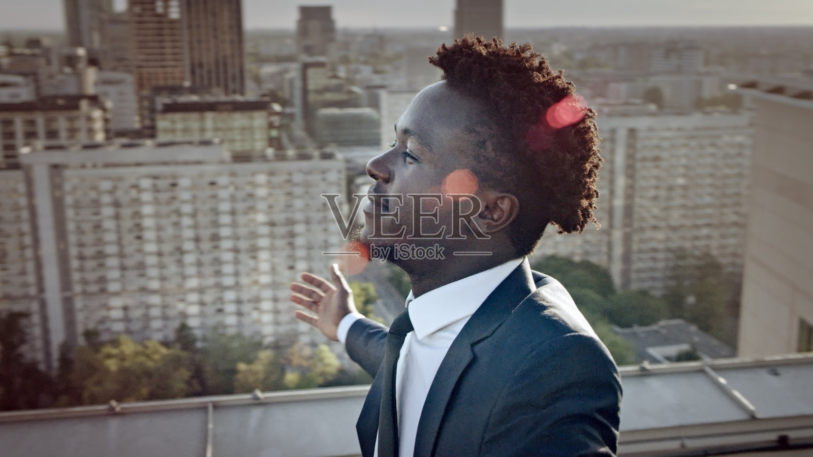 这个城市是我的。商人站在屋顶上,带着获胜的姿态照片摄影图片
