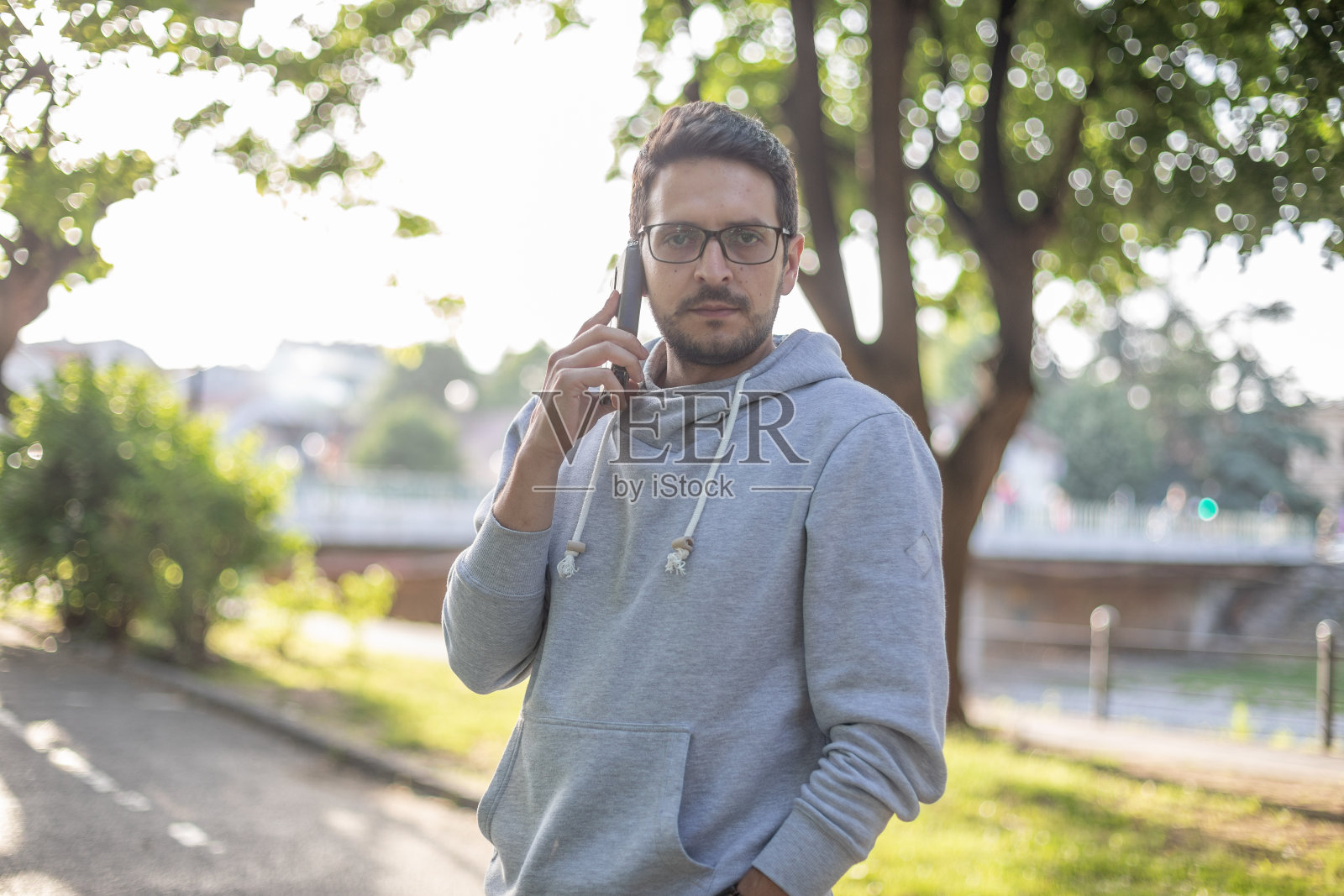 在公园里,智能手机上的帅哥,背光照片摄影图片