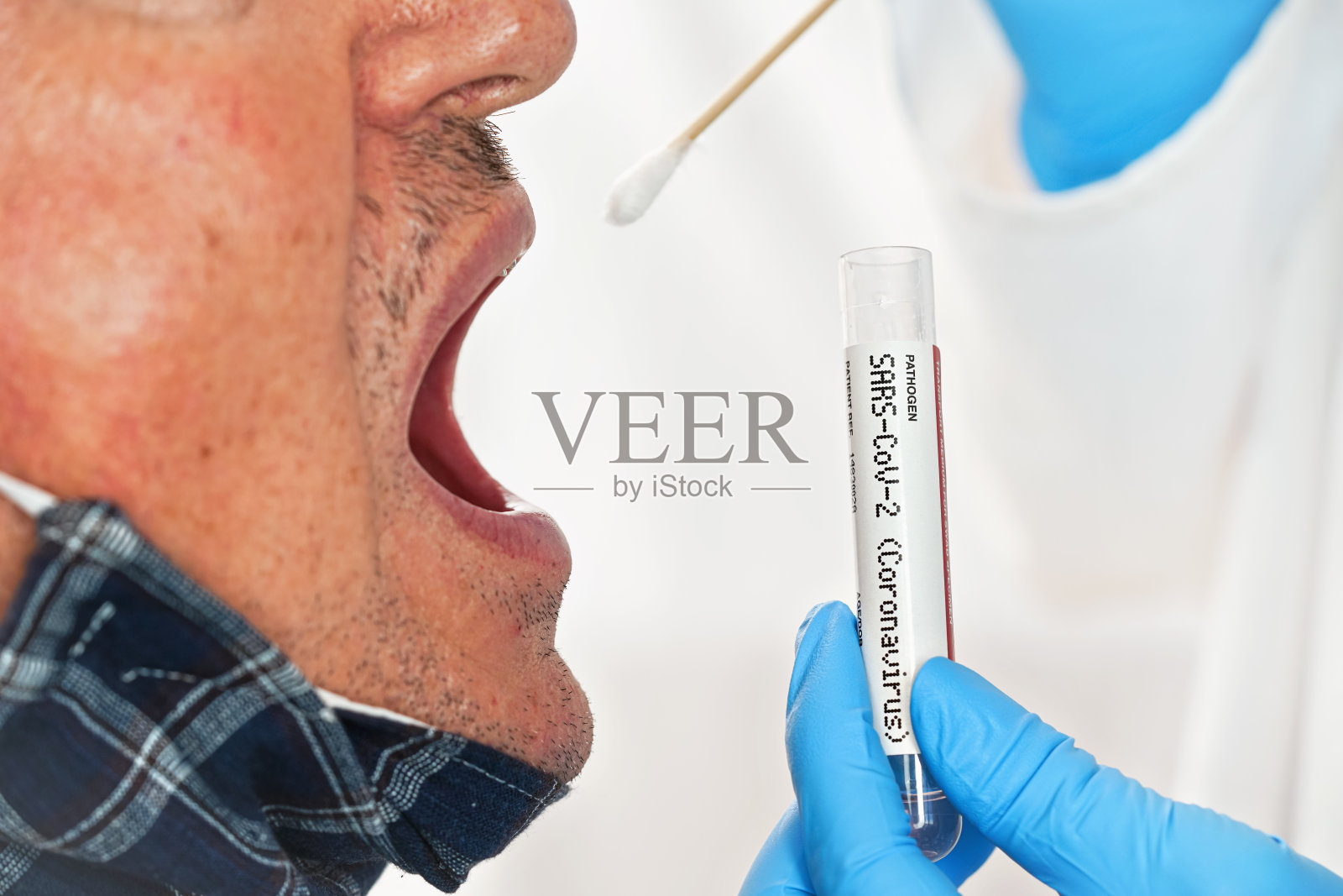 用棉签粘入老年患者张开的嘴内,用手戴蓝手套将病毒标本运送管举近,特写细节。冠状病毒covid-19检测概念照片摄影图片