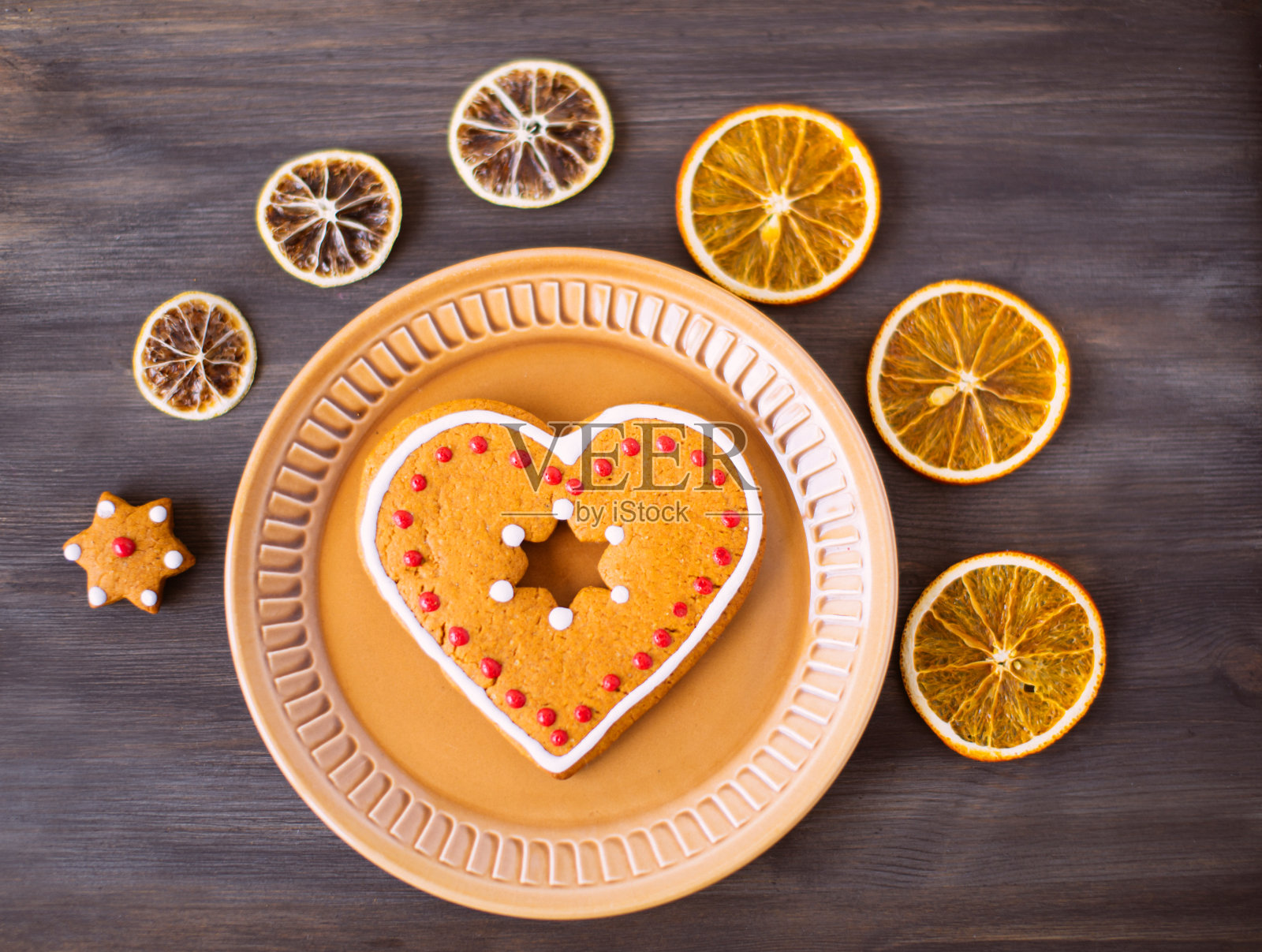 圣诞美味的饼干躺在木背景的碟子上。盘子的周围放着干橙子和圣诞饼干。照片摄影图片