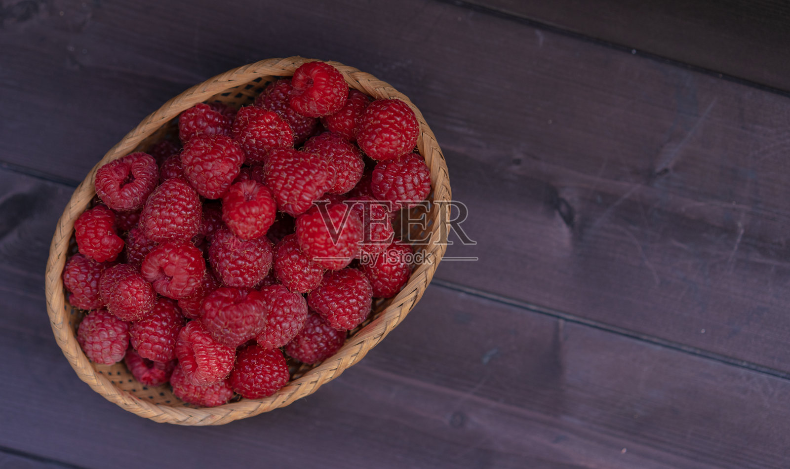 木背景上的小篮子里的覆盆子照片摄影图片