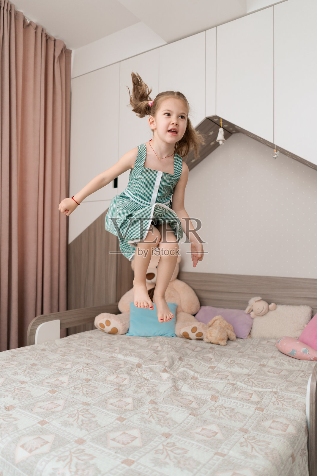 可爱的女孩在房间的床上跳照片摄影图片
