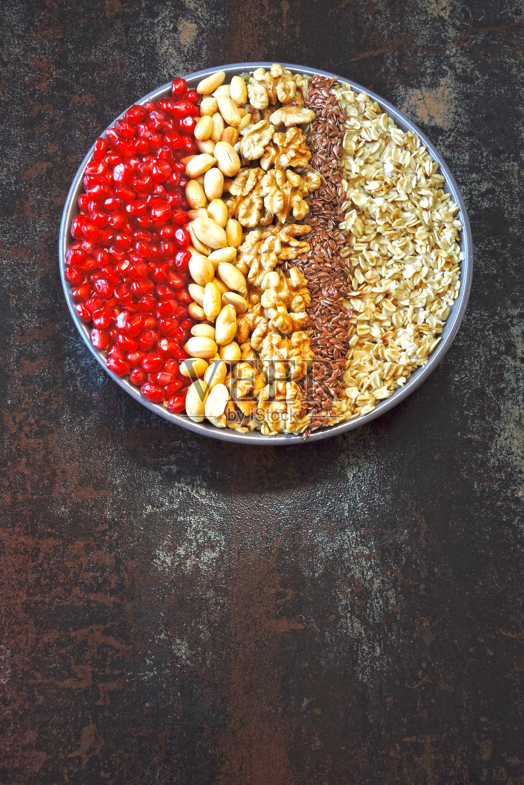 早餐一碗有坚果和石榴的燕麦粥。照片摄影图片