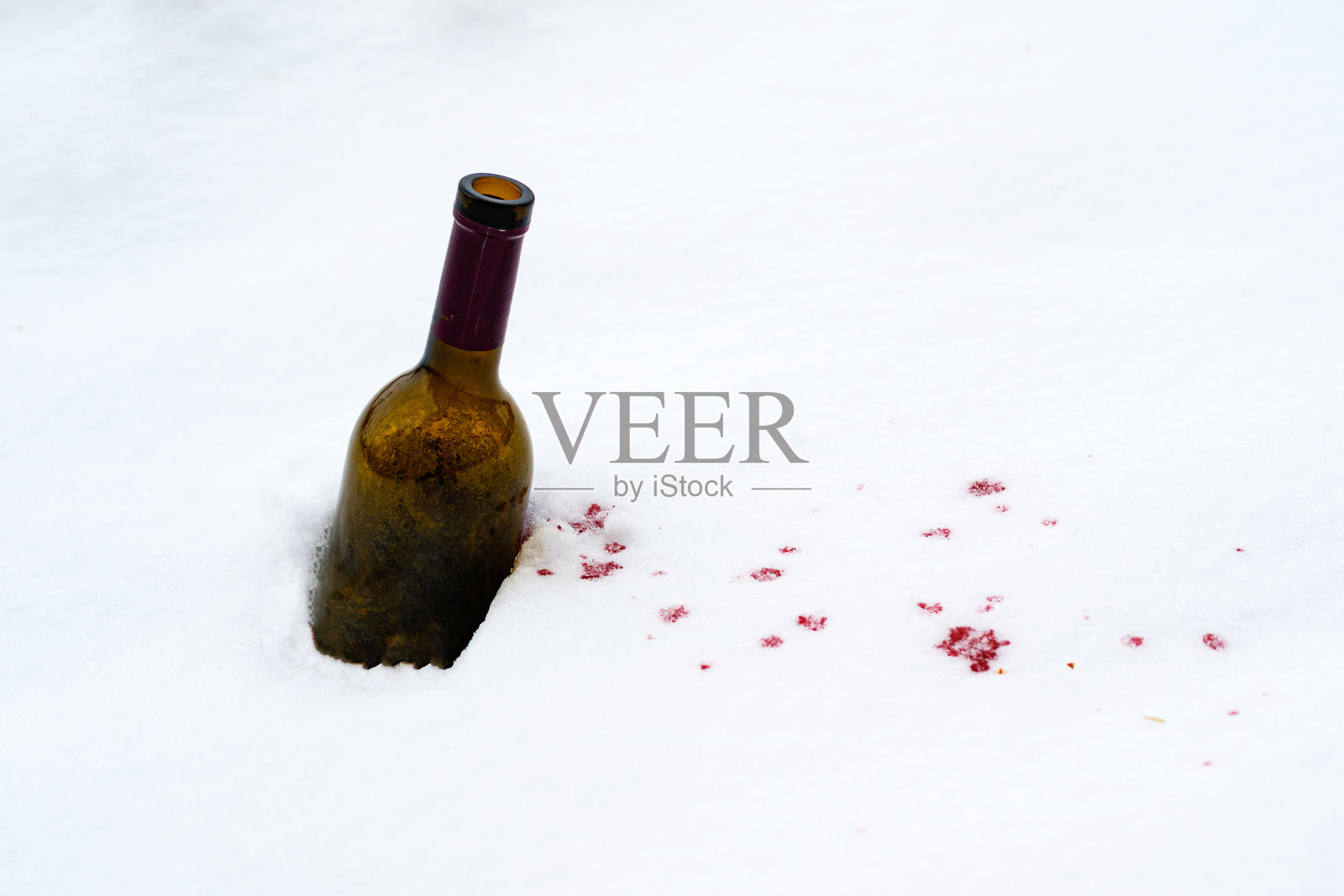 雪里的一瓶红酒洒了出来,洒在了雪地上照片摄影图片
