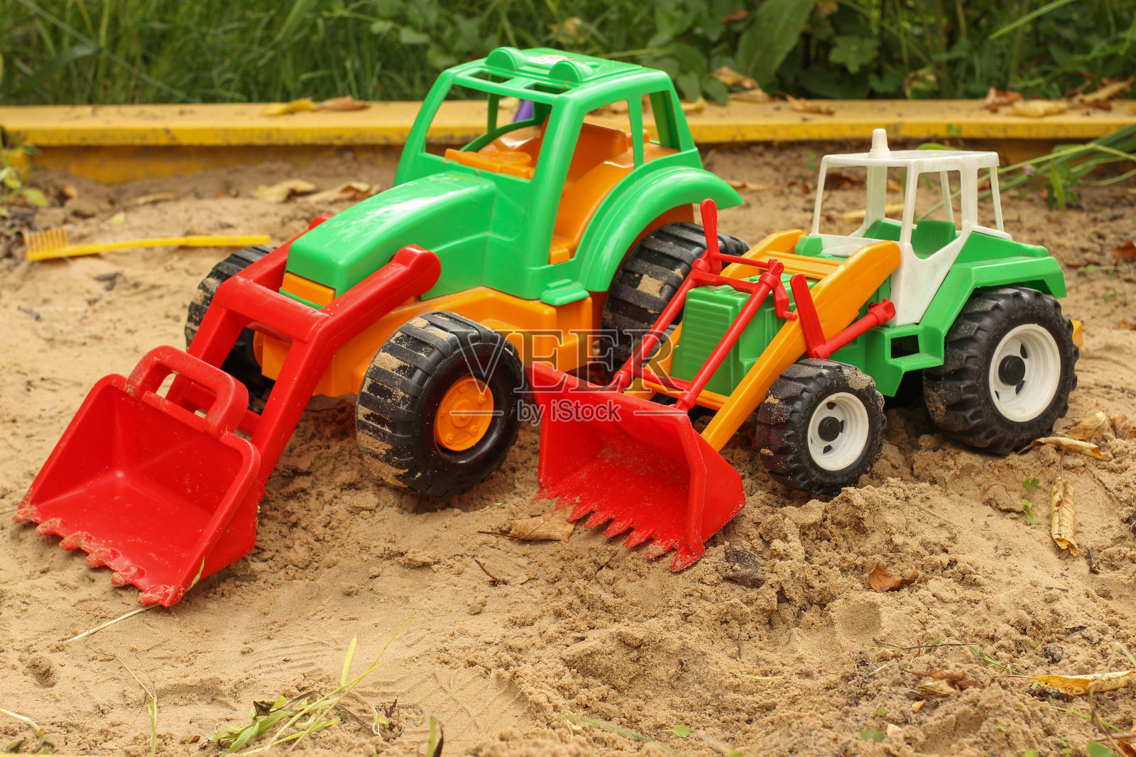 玩具拖拉机,挖土机在沙箱里照片摄影图片