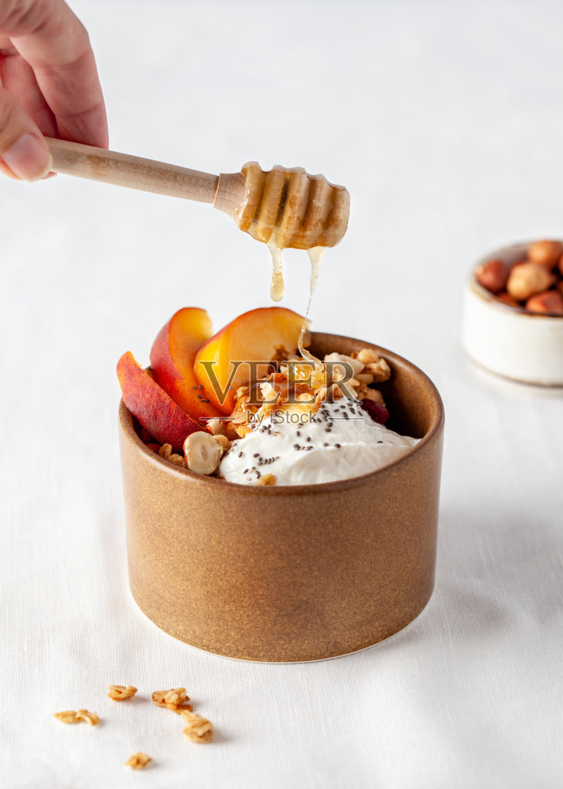 早餐。格兰诺拉麦片配酸奶,桃,奇亚籽和蜂蜜照片摄影图片