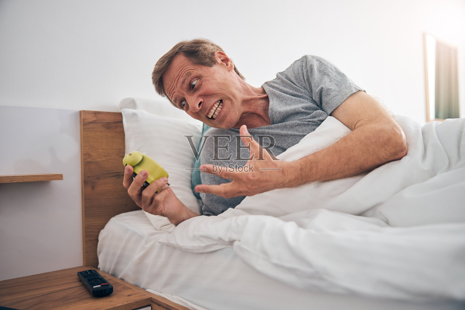 愤怒的男性对着闹钟大喊大叫照片摄影图片