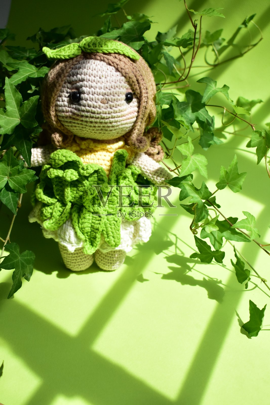 可爱的钩针娃娃以常春藤(Hedera Helix)树叶为背景,绿色柔和,淡绿色,生态友好,植物学,环保,新生活,和平的主题,复古花园照片摄影图片