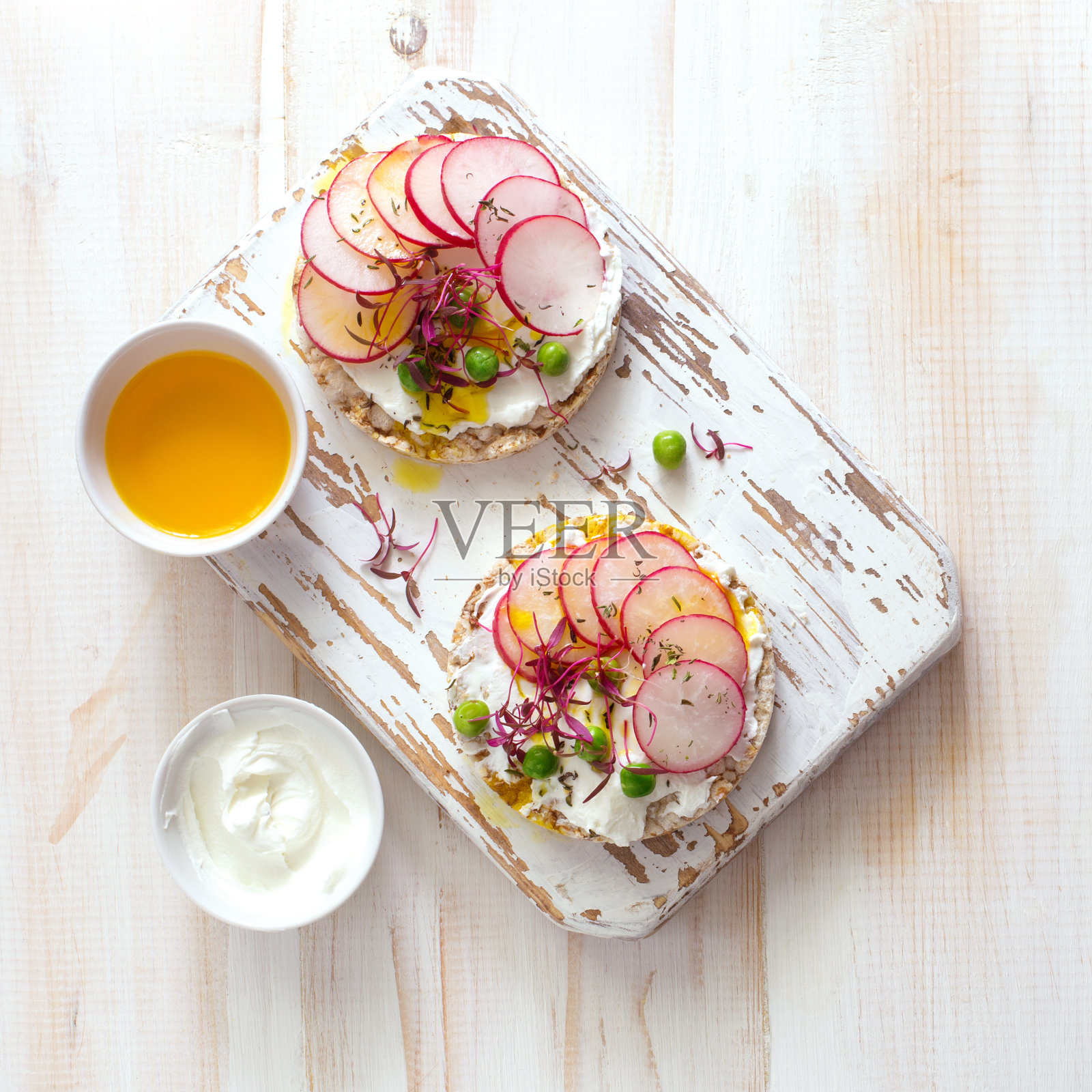 两个开放式的烤面包,配上奶油芝士、萝卜、绿豌豆和绿色蔬菜照片摄影图片