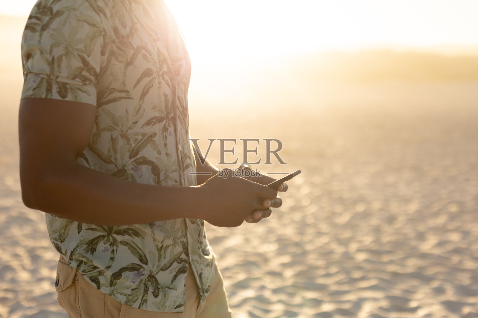 一名非裔美国男子在阳光明媚的海滩上使用智能手机照片摄影图片