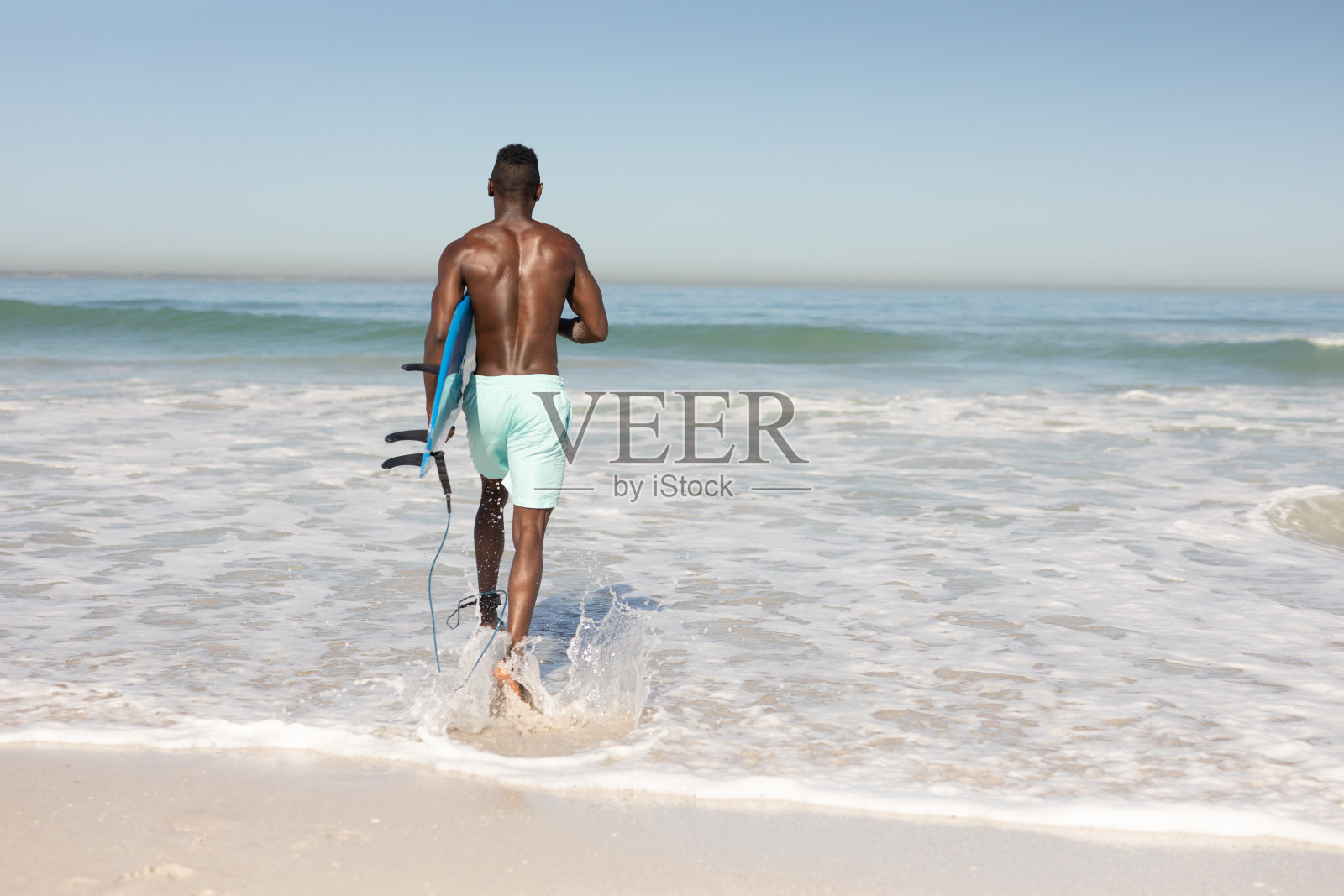 一个非裔美国人在海滩上拿着冲浪板照片摄影图片