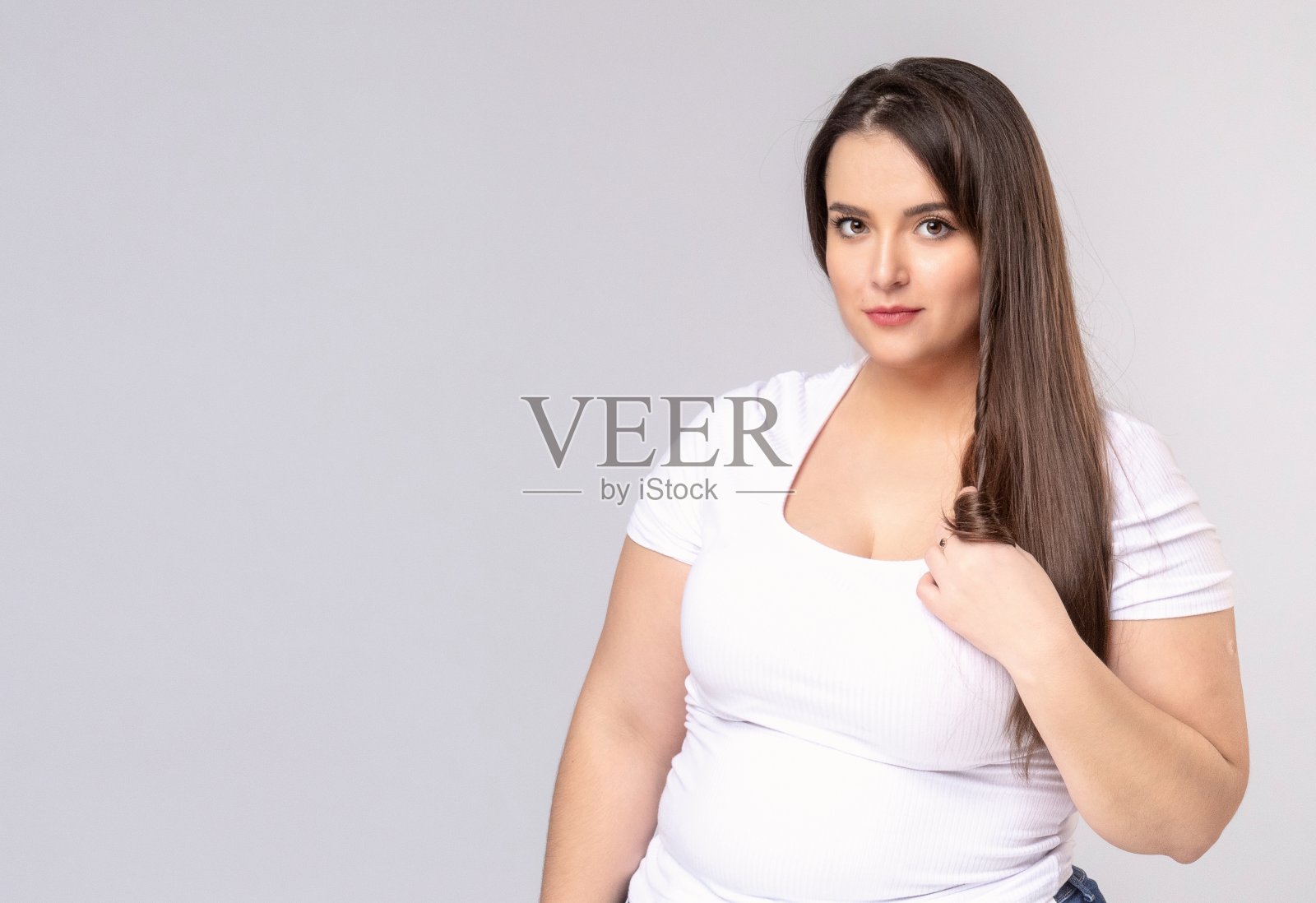 长头发的模特把手指上的头发拧成一团照片摄影图片