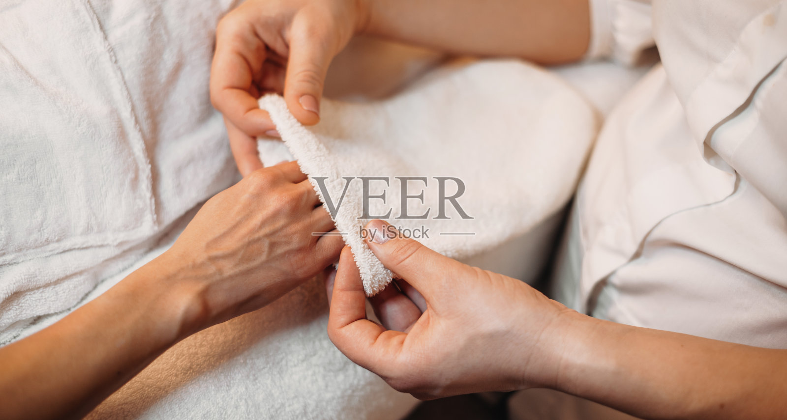 白种人按摩师在按摩后用水疗手套擦干客户的手照片摄影图片