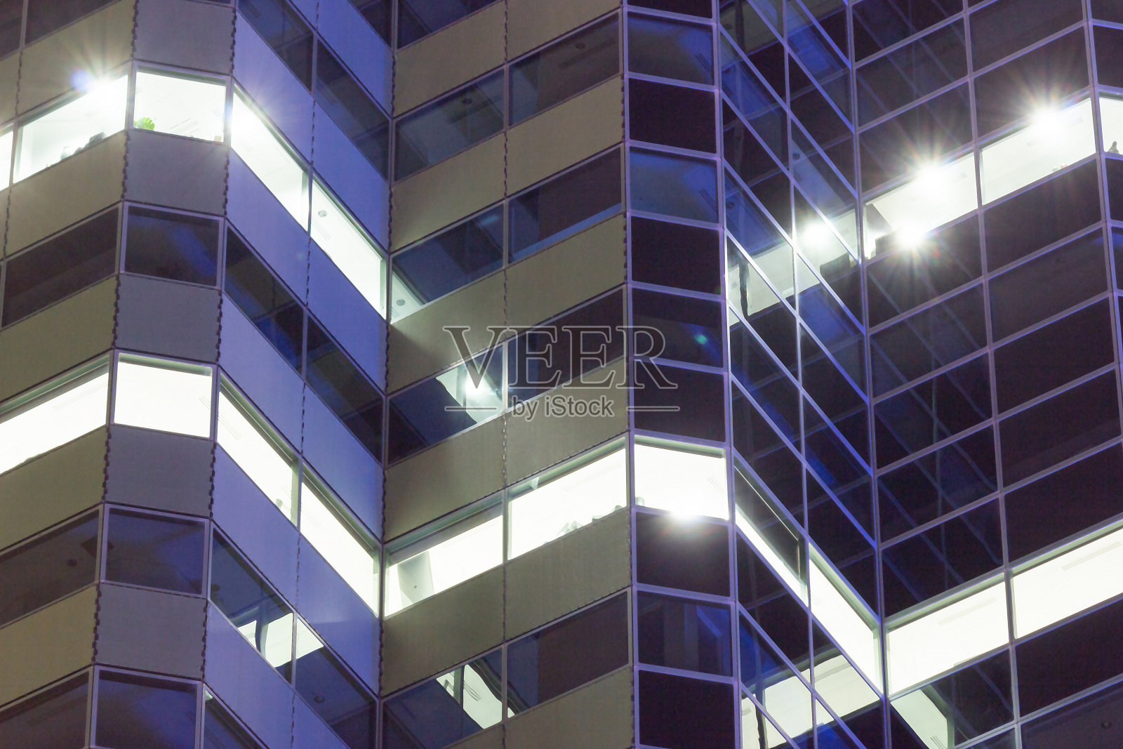 公司商务大楼的立面在晚上有灯光的窗户。照片摄影图片