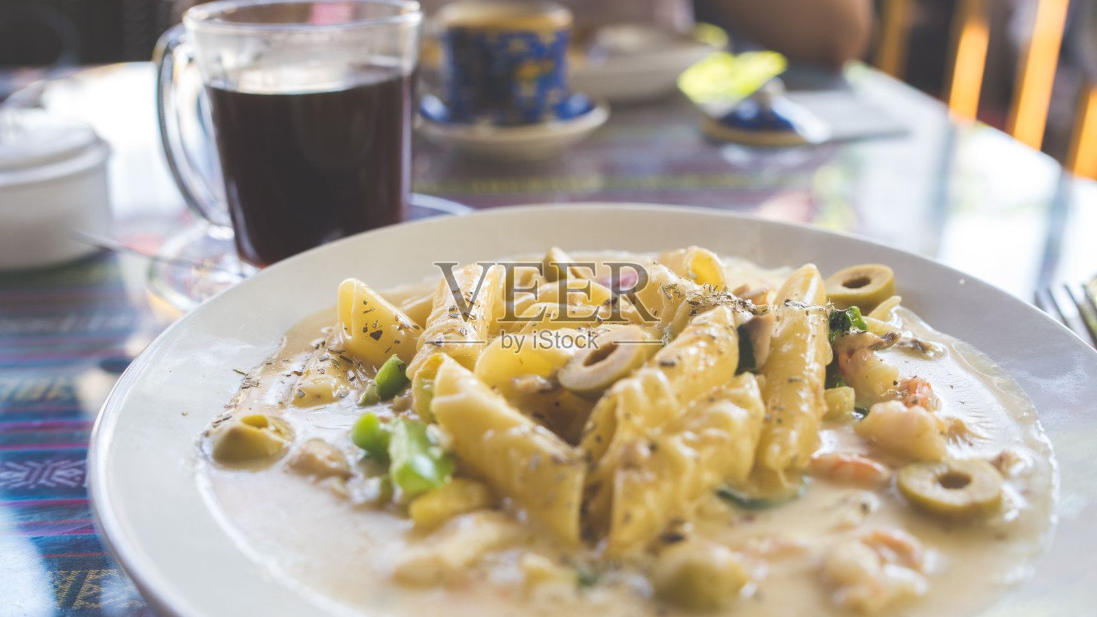 咖啡桌上有美味的意大利面。在餐厅的桌子上放着一份美味的奶油酱意大利面照片摄影图片