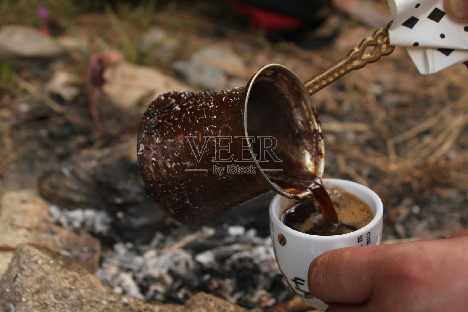 用木火煮土耳其咖啡,然后倒进杯子里的瞬间照片摄影图片