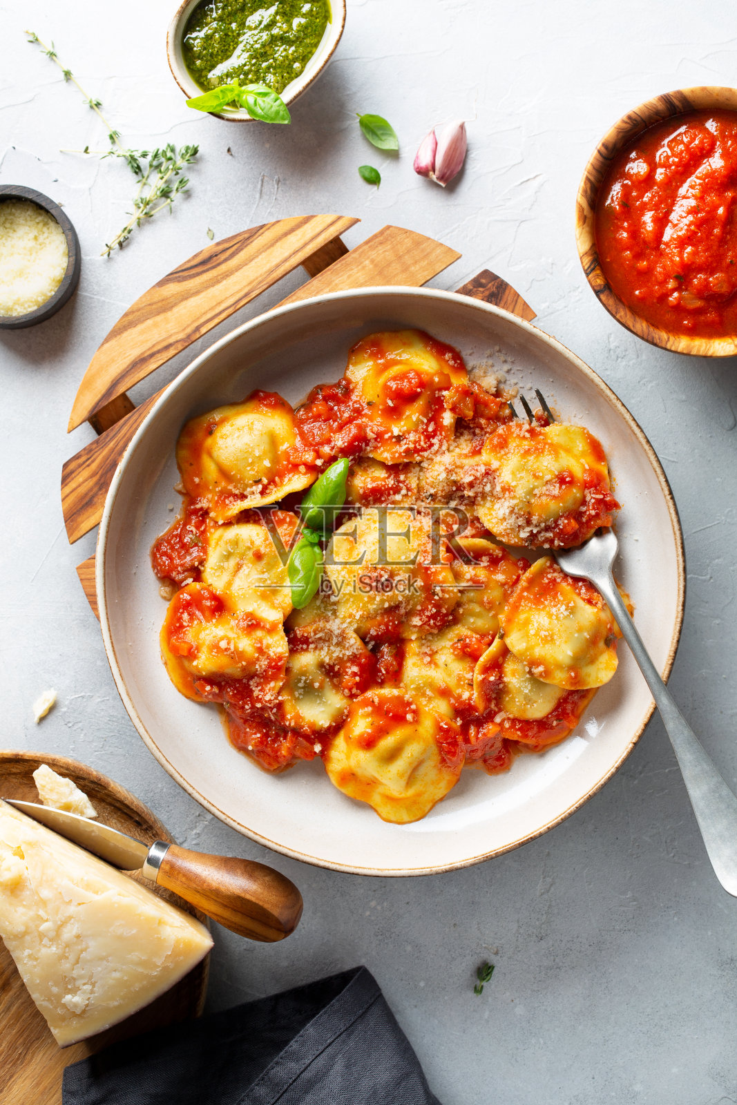 番茄酱意大利饺子。帕尔马干酪,香蒜沙司,那不勒斯沙司放在浅灰色的桌子上。传统的意大利面食。前视图。照片摄影图片