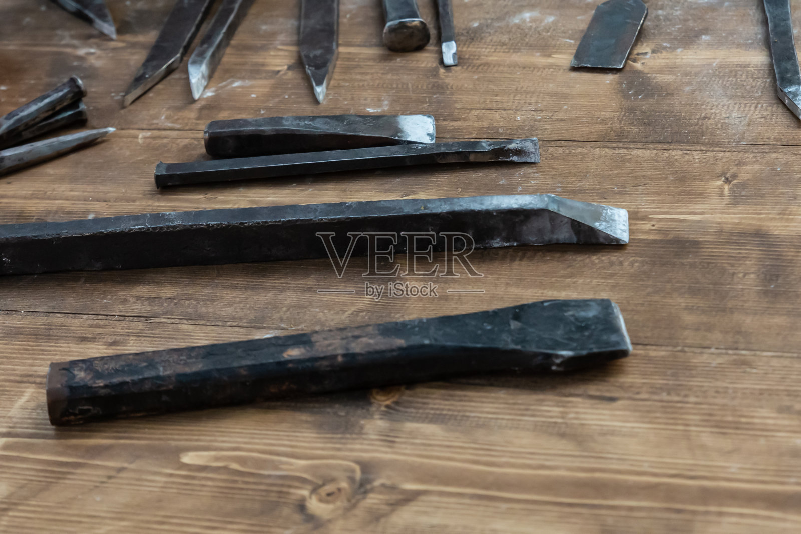 一套铁凿锋利的泥瓦匠工具躺在木桌上,在雕塑上创造一个模式照片摄影图片
