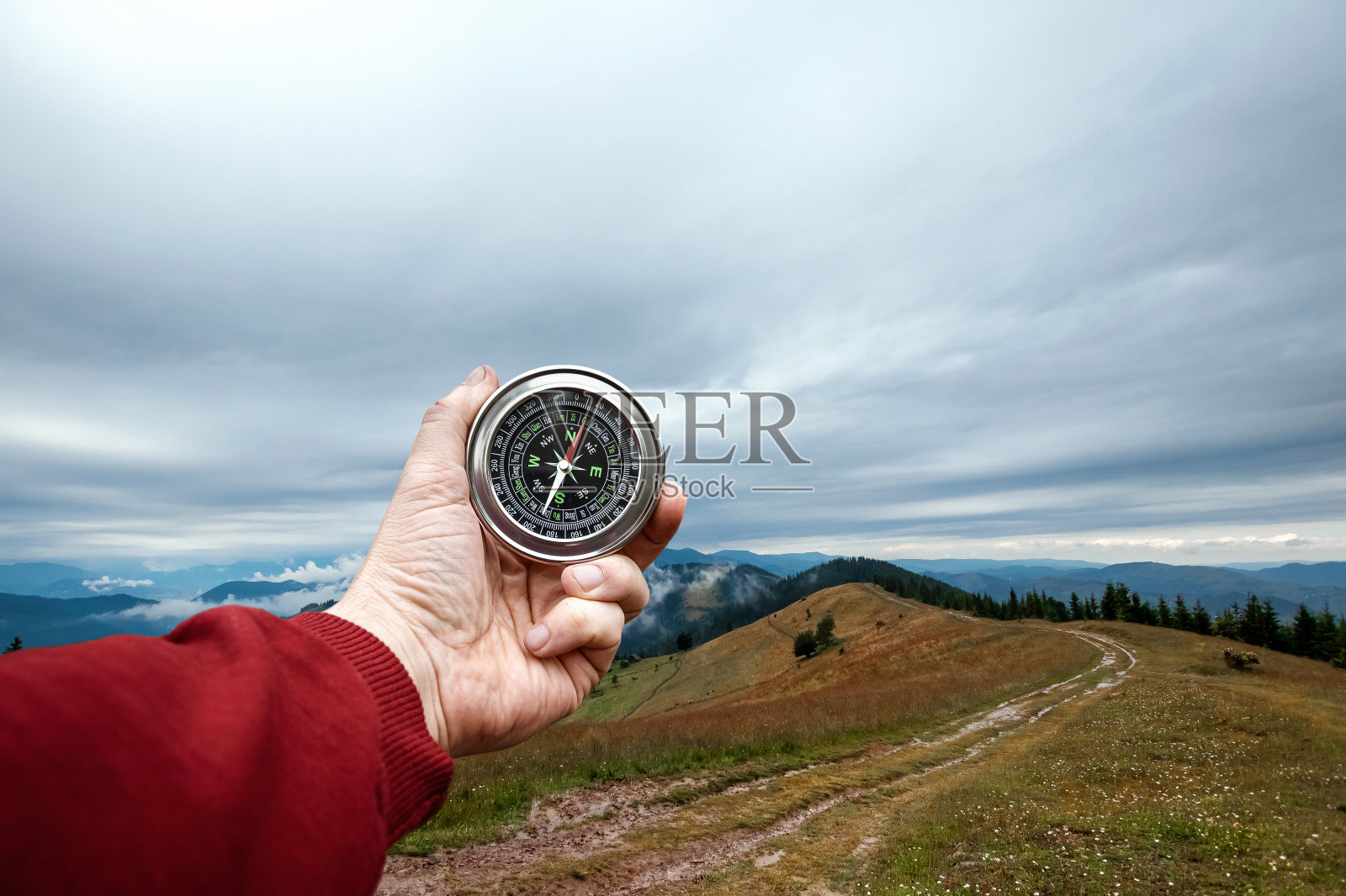 特写男性的手和银色罗盘上的背景山景观。旅行的概念,徒步旅行,帮助,搜索,度假。副本的空间。照片摄影图片