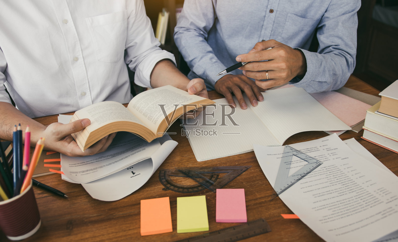 一个十几岁的学生在他的房间里做家庭作业,在笔记本上写东西。照片摄影图片