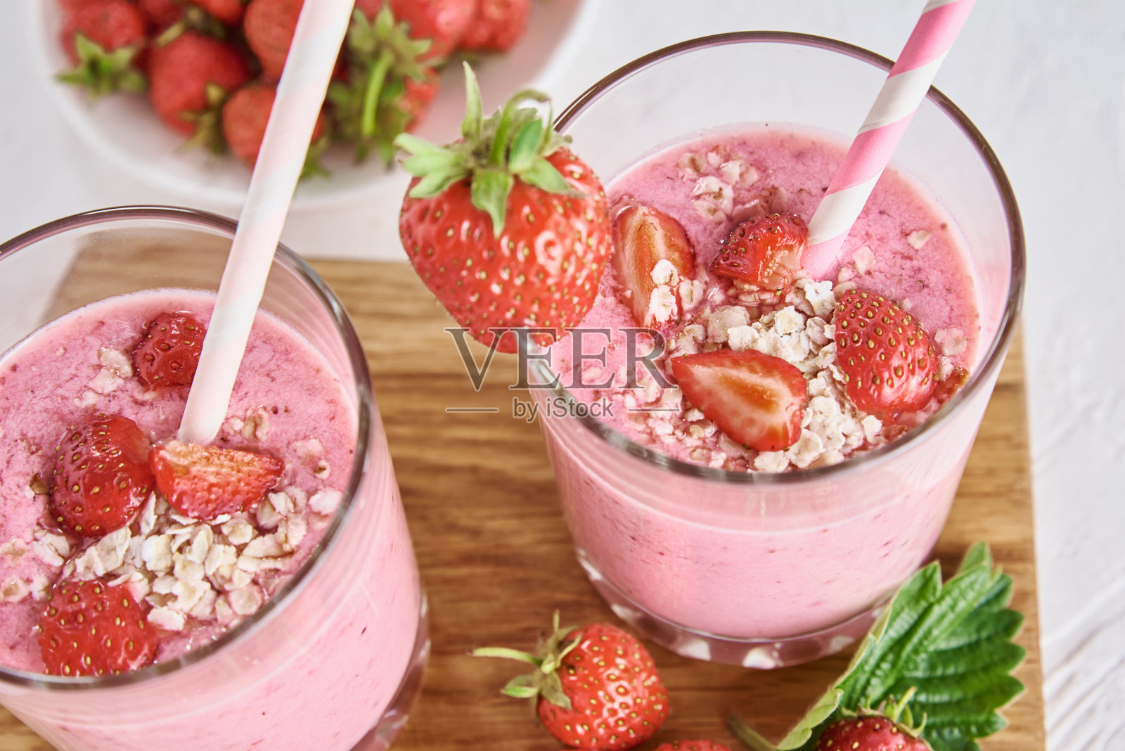 草莓奶昔在玻璃吸管和新鲜浆果在白色的背景照片摄影图片