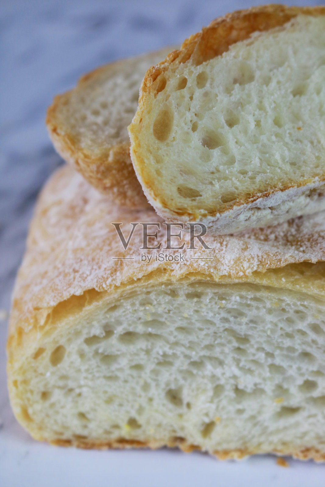 自制的脆皮意大利面包片显示纹理细节,金黄色,刚出炉的烤箱,硬面包切成薄片,大理石效果的背景照片摄影图片