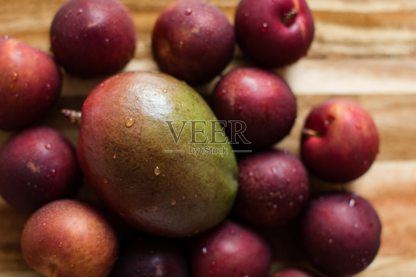 新鲜的深紫色和红色的李子和绿色和红色的芒果照片摄影图片