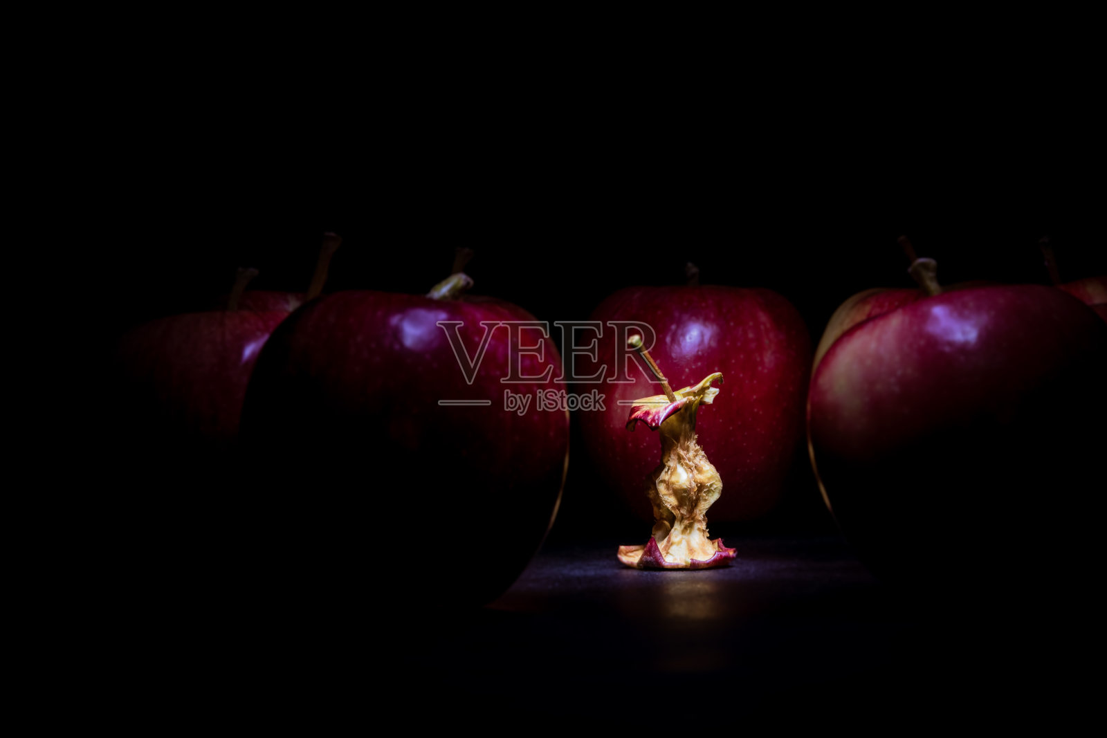 吃过的苹果周围都是成熟的红苹果。照片摄影图片