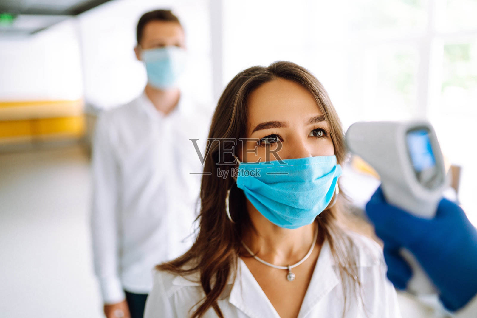 游客必须通过红外线数字体温计测量额头温度。照片摄影图片