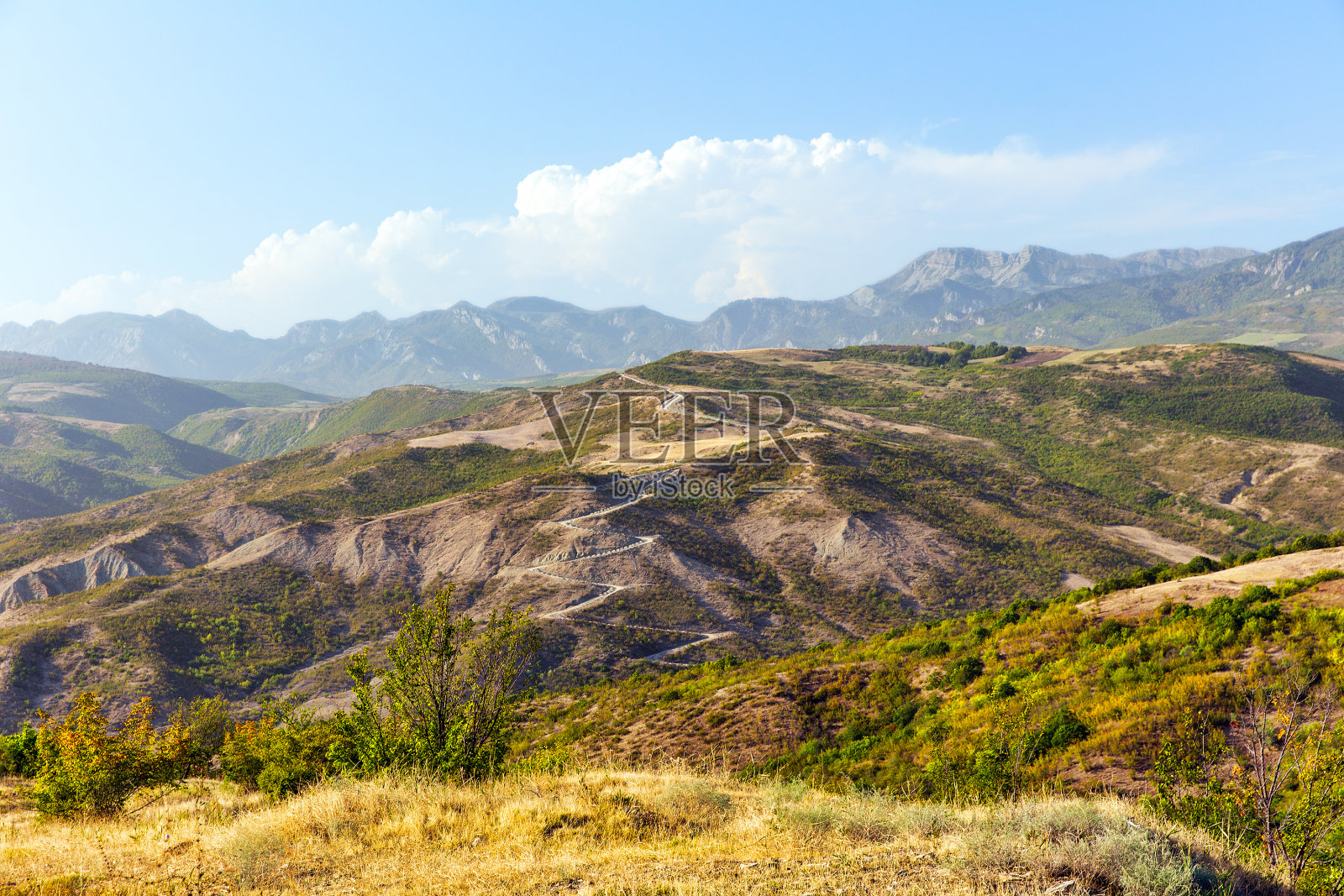 阳光灿烂的日子里蜿蜒的山路。高加索山脉在一个阳光明媚的日子照片摄影图片