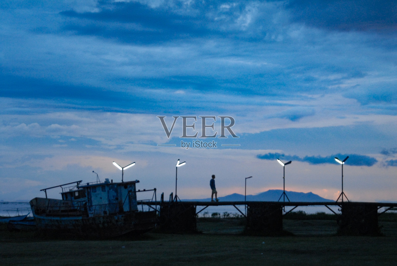 黄昏时分,一个人站在码头上的剪影照片摄影图片