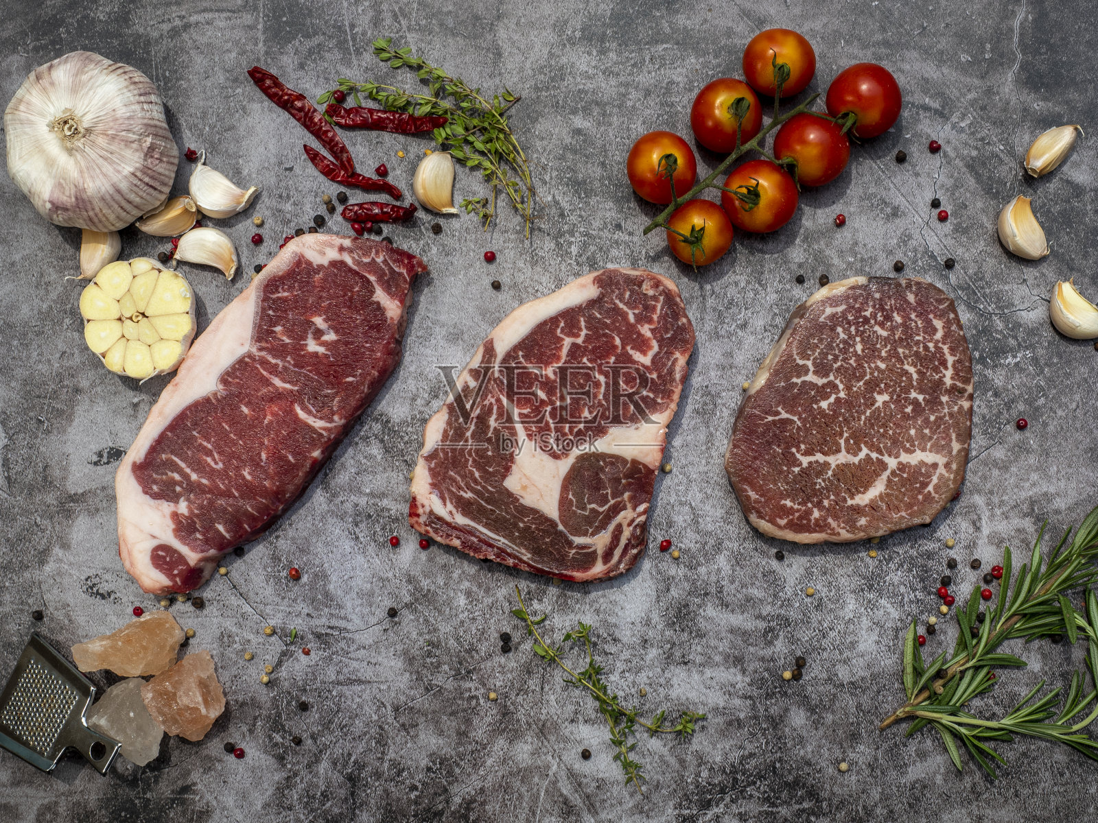 顶视图的各种切生肉排与香草在灰色的混凝土背景。准备食物的概念。照片摄影图片