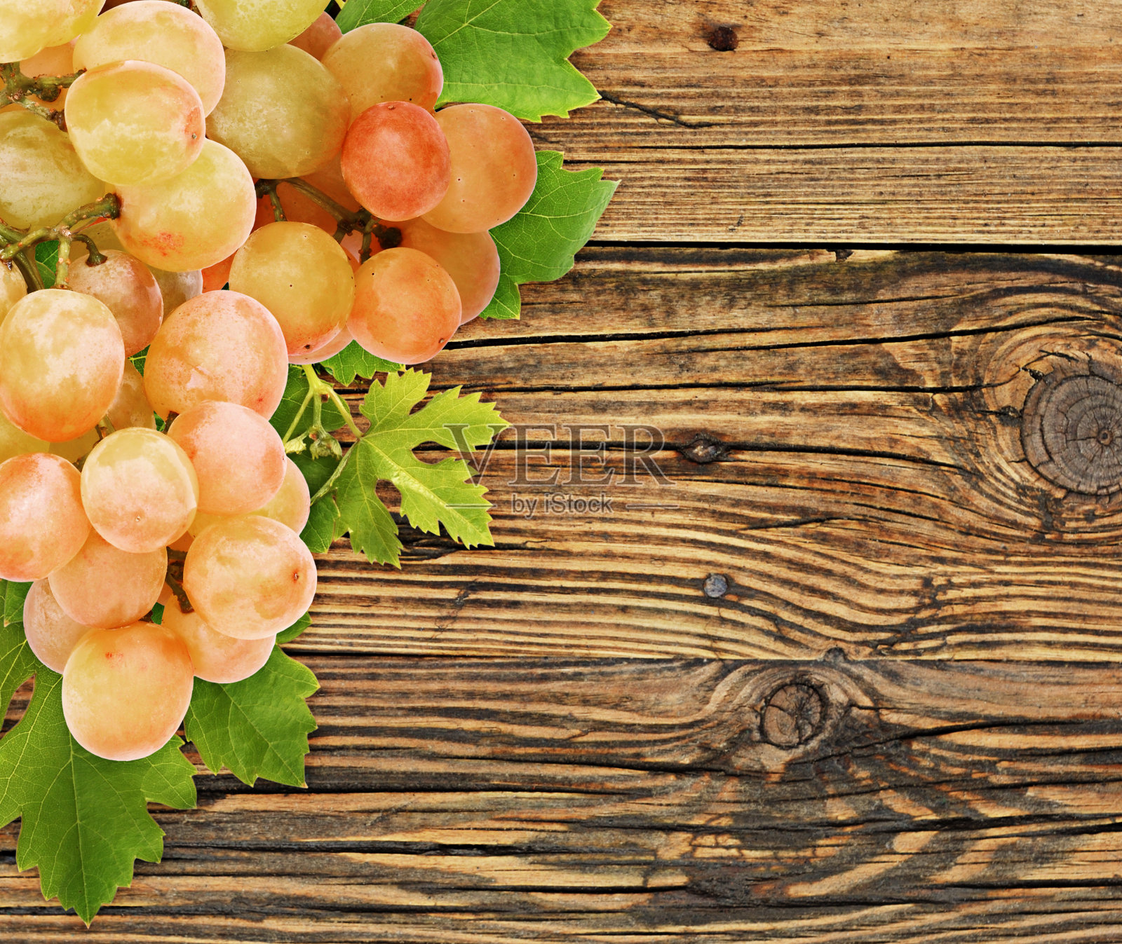 把成熟的葡萄和绿叶串在角落的木头上照片摄影图片