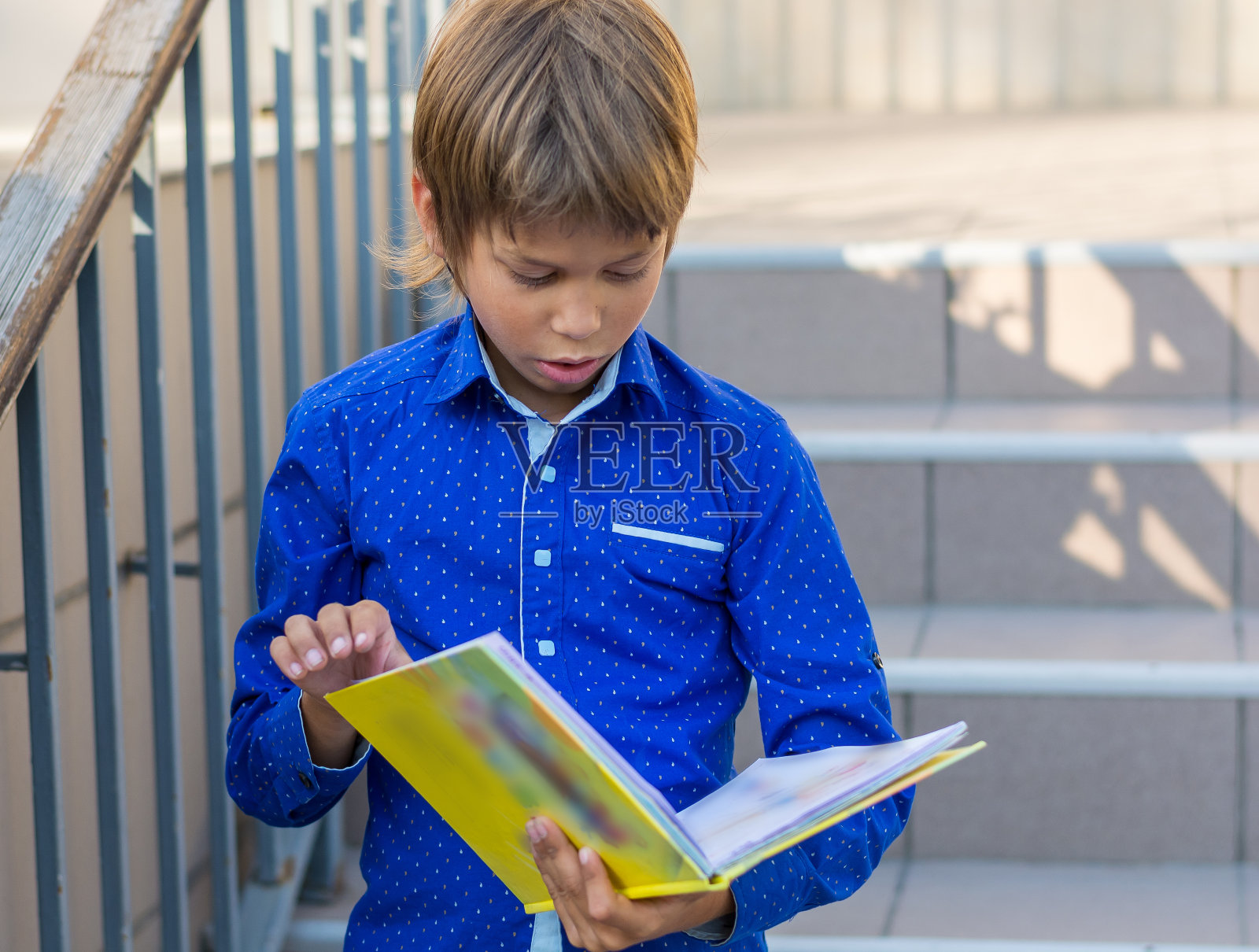 男孩在学校的门廊上玩毡尖笔和书照片摄影图片