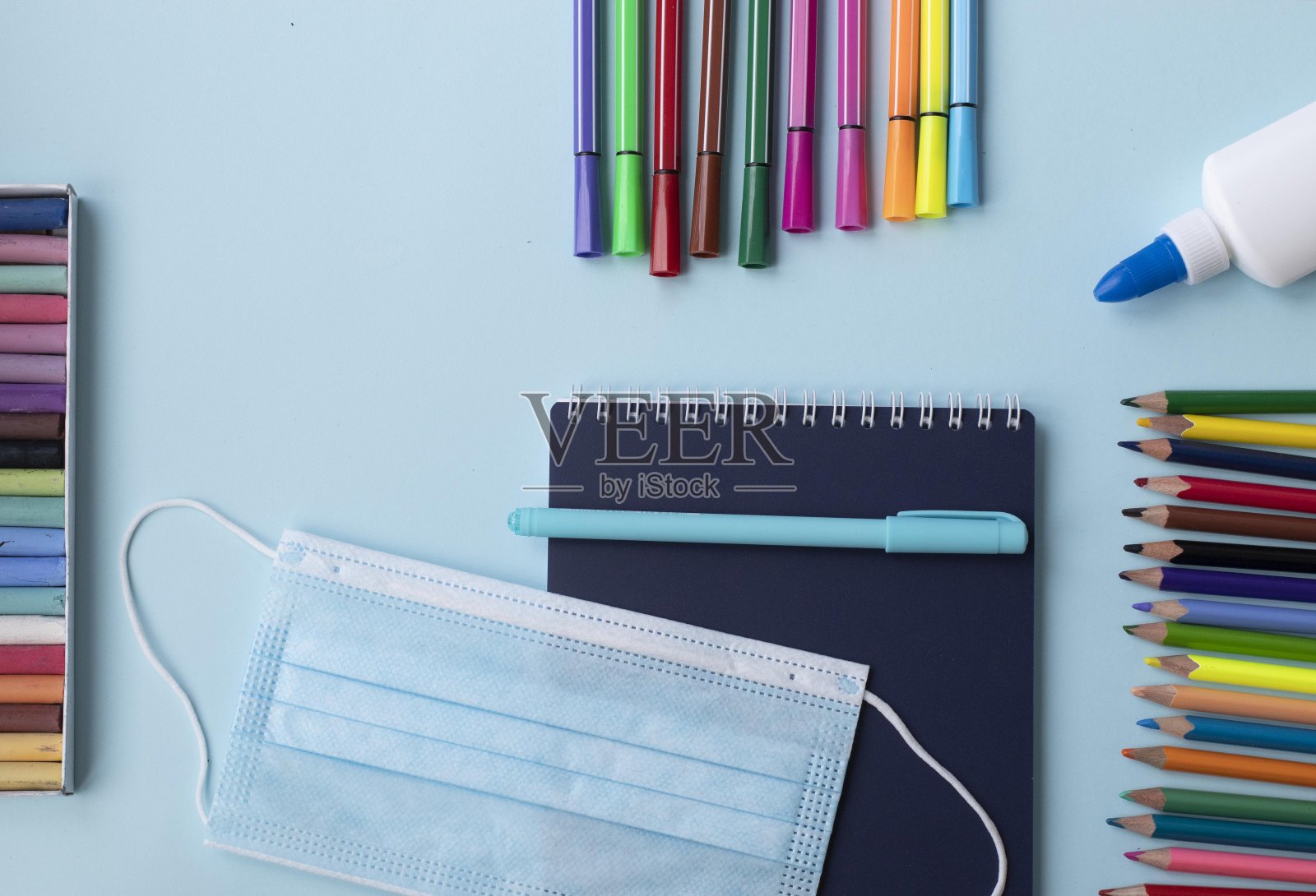 一套学校和办公用品在蓝色背景:钢笔,回别针,纸条,彩色铅笔,蜡笔,毡尖笔和闹钟。理念:回到学校。Flatlay顶视图。照片摄影图片