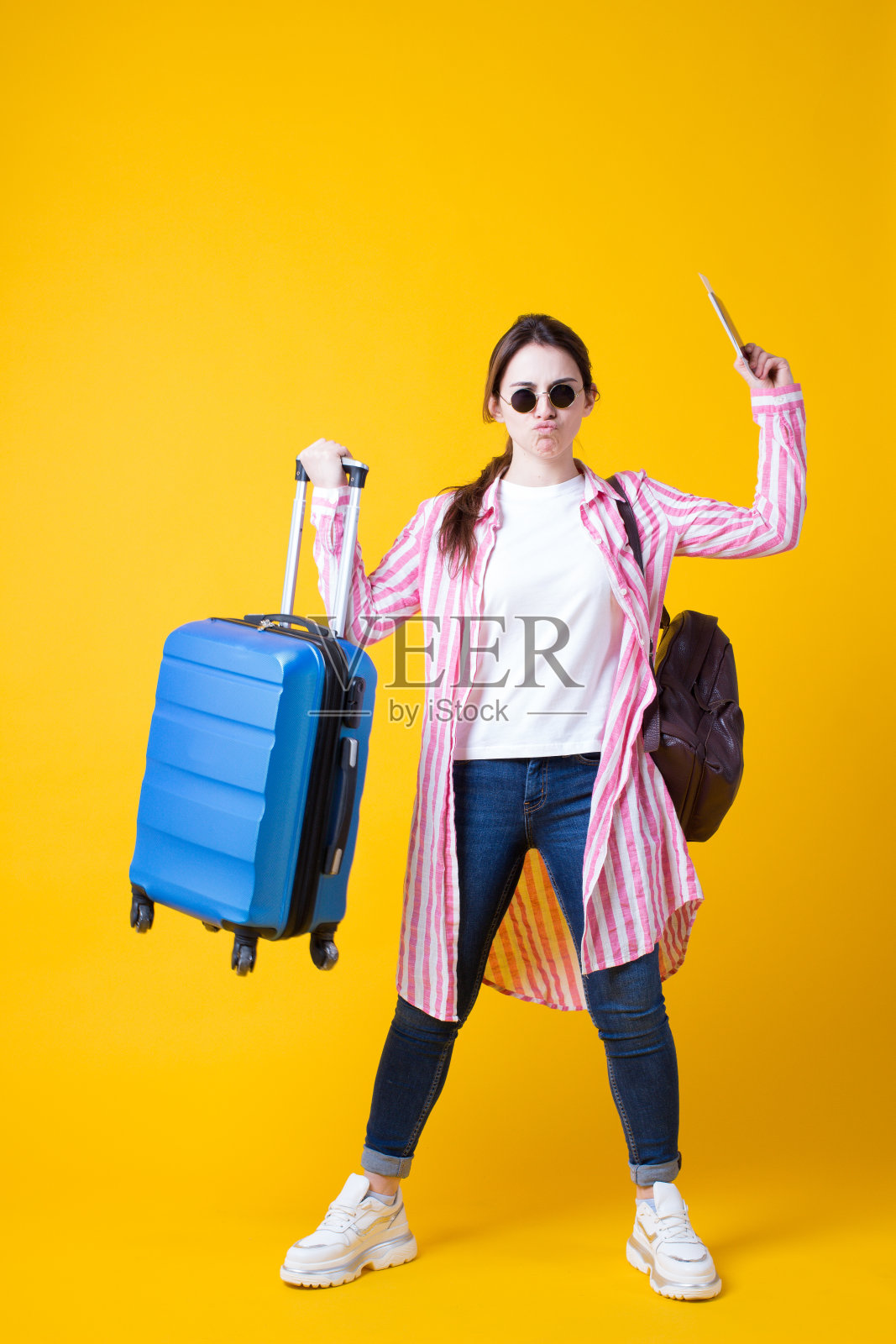 有趣的时尚的黑发旅行者女游客拿着手提箱和护照机票孤立在黄色的背景。女孩显示力量二头肌,在夏天的衣服愚弄。假期的概念。垂直照片摄影图片